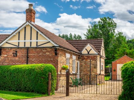 A brick cottage with tiled roof front garden hedge and metal gate at Anvil Lodge in Goulceby near Louth
