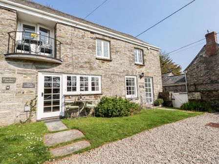 Exterior view of a stone cottage with two outdoor seating areas on a grassy lawn and gravel driveway at Slate Cottage in Tredethy near Bodmin Moor