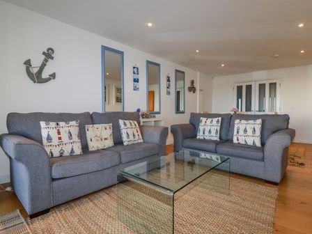 A living room with two grey sofas and a glass coffee table at 47 Bredon Court in Newquay