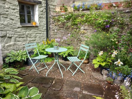 A garden with chairs and a table surrounded by plants at Arllen Fawr in Llanrhaeadr-ym-Mochnant