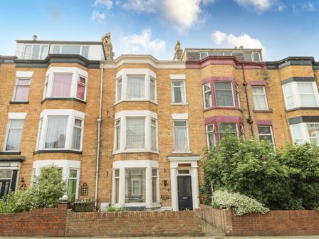 A row of brick townhouses with bay windows and small front gardens at Sanderling in Scarborough