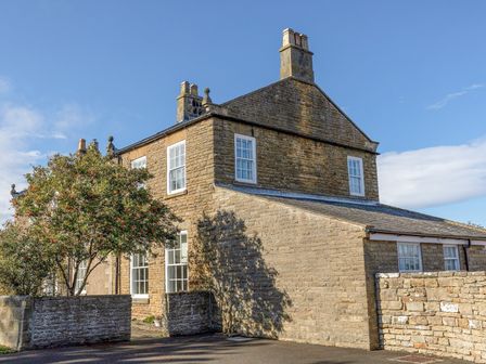 A stone house with multiple chimneys and white framed windows at Apartment 1 Sneaton Hall in Sneaton near Whitby
