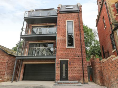 A multi-story brick building with balconies and a black garage door at The Office Gardens Apartment 2 in Whitby