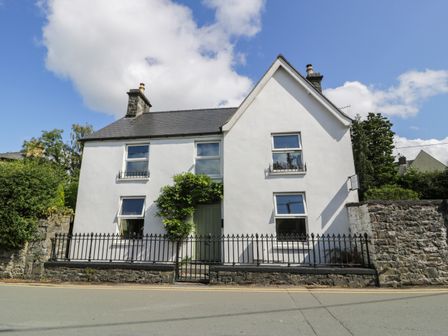 The exterior of a white two-story house with a slate roof and a black iron fence at Dale Cottage in Llanrwst