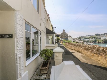 A narrow street with a stone wall and house exterior at The Watch Below in Polruan