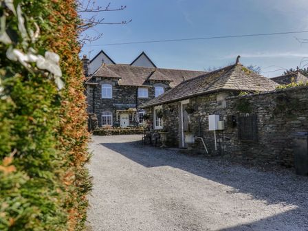 A stone house with a gravel driveway and a hedge on the left at Ees Wyke Studio in Sawrey