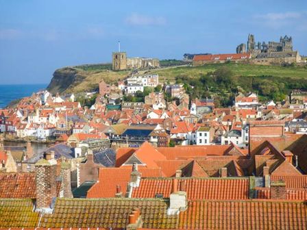 A coastal town with red rooftops and historic buildings on a hillside near the sea at High Ridge in Whitby