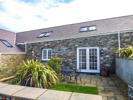 An outdoor patio with a metal table and chairs stone walls and plants at Y Wylan Holyhead