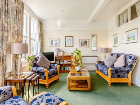 A living room with floral upholstered armchairs and sofa coffee table side tables and framed pictures on the walls at Clooneavin Apartment 3 Lynmouth near Lynton