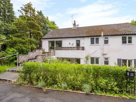 A white two-story house with a staircase and greenery in front at Tanglewood in Rhos-On-Sea
