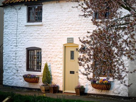 A cottage exterior with a door and flower pots at Clara's Cottage West Lutton near Malton