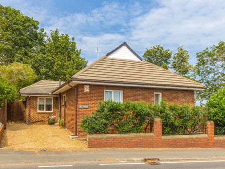 A brick house with a gravel driveway and bushes along a brick wall at Estuary View in Warkworth