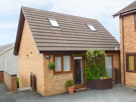 A brick house with two skylights and plants near the door at Penylodge in Builth Wells