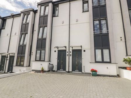 The front exterior of a modern townhouse with two dark doors numbered 5 and 6 and large windows at 5 Ocean Heights in Newquay