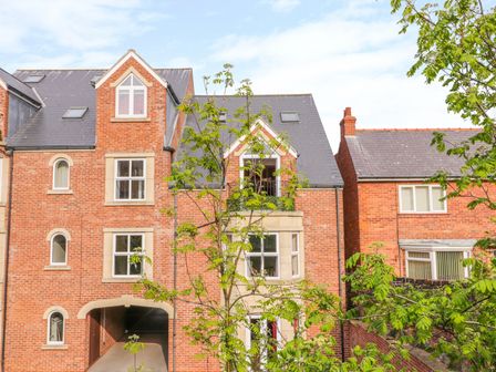 A brick residential building with multiple windows and a small tree in front at Treasure Chest in Whitby