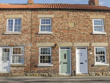 A brick terraced house with green and white doors and windows at 31 Outgang Road in Pickering