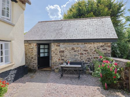 An outdoor seating area with a table and flowers at The Old Workshop Knowstone