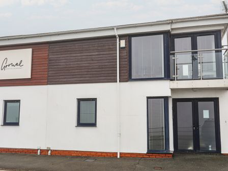 Exterior view of a two story building with windows and glass doors with a sign reading Gornel Dental Academy at 3 Marina View in Pwllheli