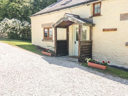 Front entrance of a farmhouse with wooden porch and flower boxes on a gravel path at Lower West Curry Farmhouse in Launceston