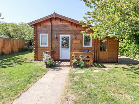 A wooden cabin with a small porch and garden path at Aurora Skies in Cresswell near Morpeth