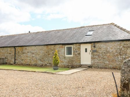 An outdoor view of a stone cottage with a front door at Gallow Law Cottage in Bellingham
