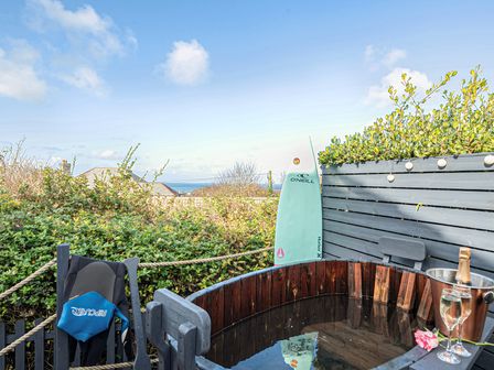 An outdoor area with a hot tub and surfboard at Sunset View in Porth