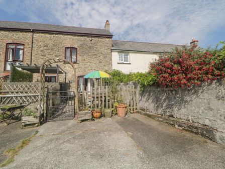 A stone house with a gate and flower pots in front at The Orchard in Okehampton