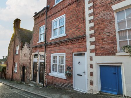 A street view of brick cottages with white and blue doors at St Marys Cottage in Scarborough