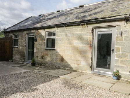 Exterior view of a stone building with two glass doors two windows and potted plants on the ground at Lowdale Barns West in Sleights