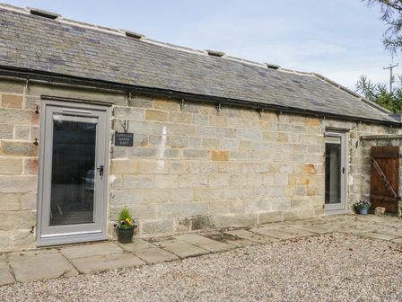 The exterior of a stone building with two glass doors and potted plants at Lowdale Barns East Sleights