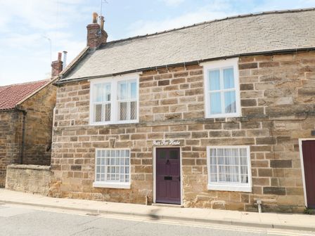 A stone house with four windows and a purple door on a street at Pear Tree House in Ruswarp