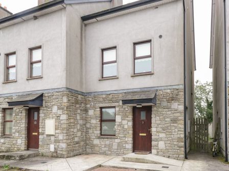 A two-story semi detached house with stone lower walls and concrete upper walls with wooden doors and windows at Aisling in Foxford near Ballina County Mayo
