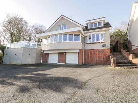The exterior of a house with two garage doors a driveway and steps leading to an upper entrance at 11 Glyn Garth Mews Llandegfan near Beaumaris