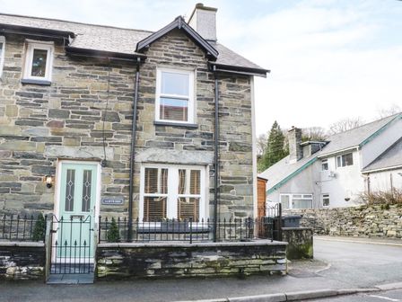 Stone house with a light green door and small front garden with iron fence at Llwyn Onn in Dolwyddelan