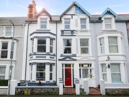 A terrace house with a red door and bay windows at Abbeylands House in Llandudno