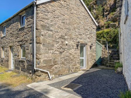 Exterior view of a stone building with white framed windows and doors beside stone steps and gravel driveway at Ty Cynon Blaenau Ffestiniog