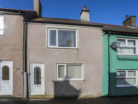 A front view of a two-story terraced house with white doors and windows at The Old Post Office 23 High Street in Cemaes Bay