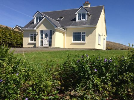 A detached house with a pitched roof surrounded by greenery and flowers at The Slate House in Cahersiveen County Kerry