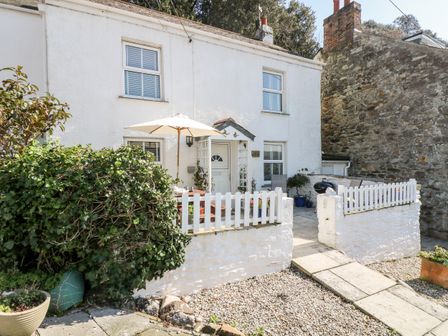 Front patio area with a table umbrella white picket fence and shrubs at Mallards in Pentewan