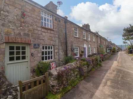 A cottage facade with a sign at May Cottage in Pentewan