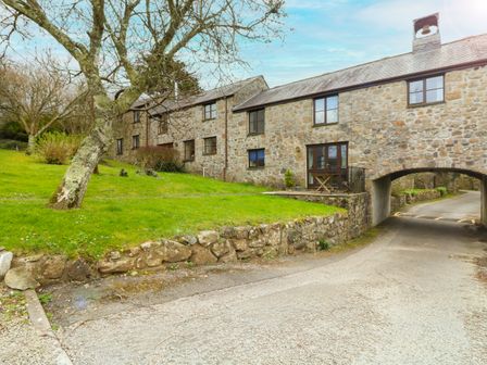A stone cottage with grass and trees beside a driveway at Bell Cottage in Gulval near Marazion