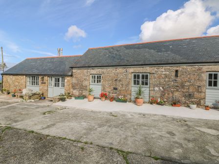 A stone building with multiple doors and windows with potted plants outside at Back Of Beyond in St Ives