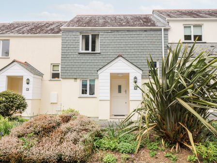 Front view of a two story house with a tiled roof and garden at Compass Point in Falmouth