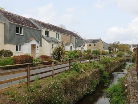 A row of houses with a footpath and wooden fence next to a small stream at Mulberry Cottage in Falmouth