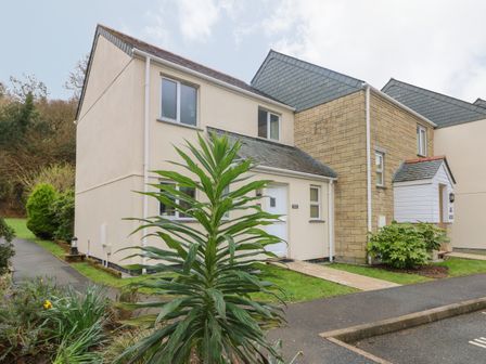 A modern residential building with a light exterior and adjacent greenery at Morton Cottage in Falmouth