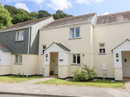 Exterior view of a two story beige building with two entrances and small garden at Trelease in Falmouth