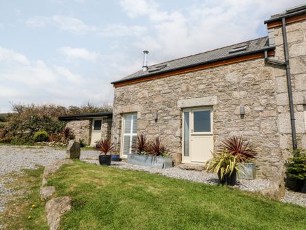 Exterior of a stone building with a grass lawn and potted plants at Leghorn in St Austell