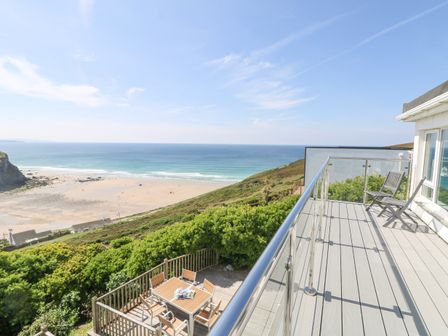 A balcony with chairs overlooking a sandy beach and ocean at St Ives View in Porthtowan