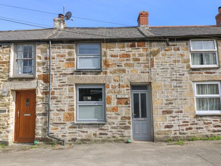 A stone facade house with two doors and two windows and a chimney at Trevean in Portreath
