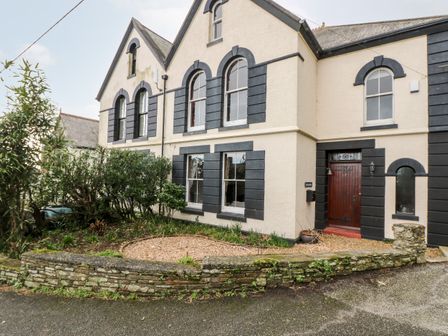 Exterior view of a two story house with stone wall and garden at Penare House in Mevagissey